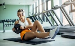 young-athletic-woman-exercising-situps-with-weight-plate-gym_637285-8526