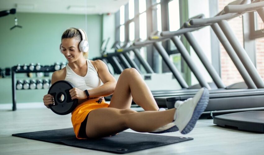 young-athletic-woman-exercising-situps-with-weight-plate-gym_637285-8526