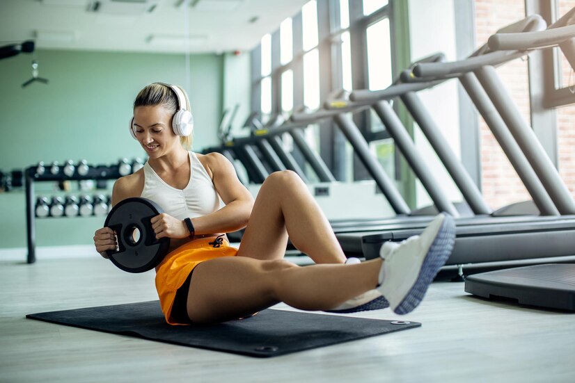 young-athletic-woman-exercising-situps-with-weight-plate-gym_637285-8526